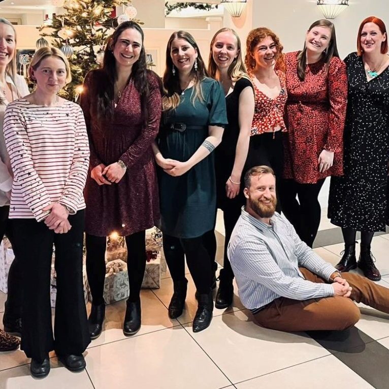 Happy Vet Times Jobs recruitment customers. An image of nine people in front of a Christmas tree - the team at Strand Vets.